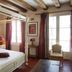 La Demeure Saint-Ours in Loches: four-poster bed in a rustic guest room with wood beams and tall windows