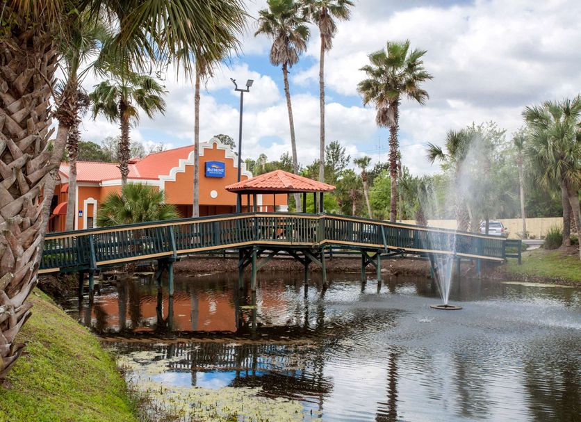 Baymont Inn & Suites Lake City with palm-lined pond, fountain, and bridge beside the hotel