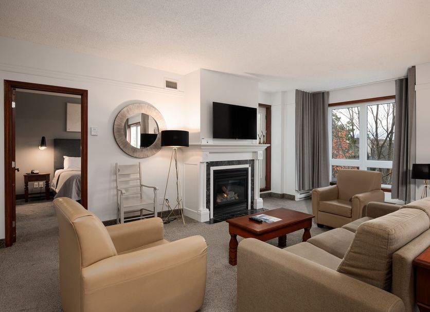 Sommet Des Neiges in Mont-Tremblant living room with fireplace, TV, beige seating and mountain-view windows