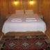Cirali Almira Bungalow in Cirali: cozy wooden bungalow room with double bed, bedside lamps, and patterned rug.