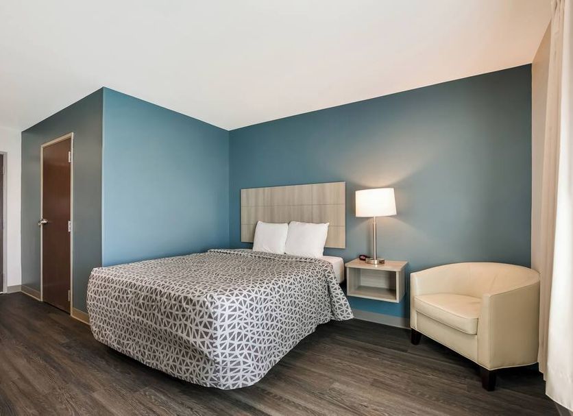 WoodSpring Suites Morrisville - Raleigh Durham Airport guest room with bed, lamp and chair in Morrisville