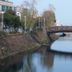 Jeju Stay Hotel in Jeju City overlooking a calm canal with a wooden bridge and reflections