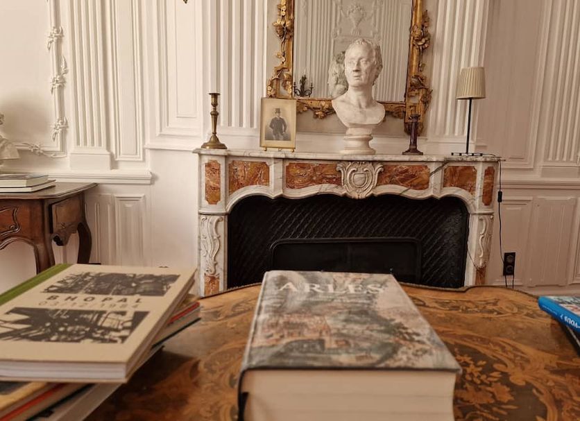 Palais de Luppé in Arles: ornate guest room with marble fireplace, bust, and antique table with books