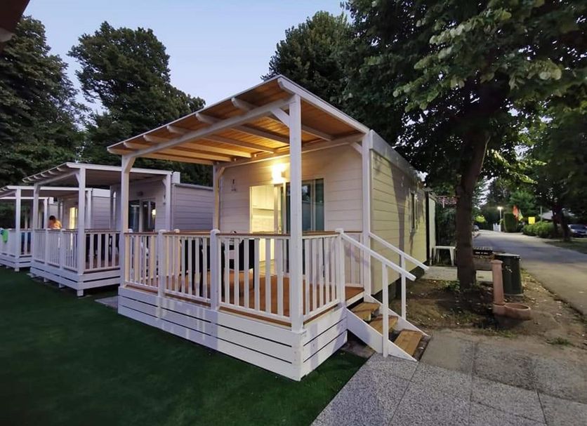 Camping Serenissima in Malcontenta: illuminated cabin-style lodging with porch and steps beside trees
