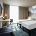 ibis Styles Lille Neuville en Ferrain room with two beds, desk, and cityscape mural in Neuville-en-Ferrain