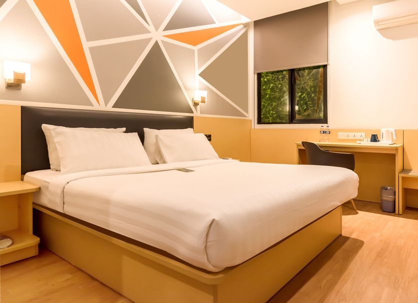 Juno Jatinegara Jakarta guest room with double bed, geometric accent wall, and desk in Jakarta
