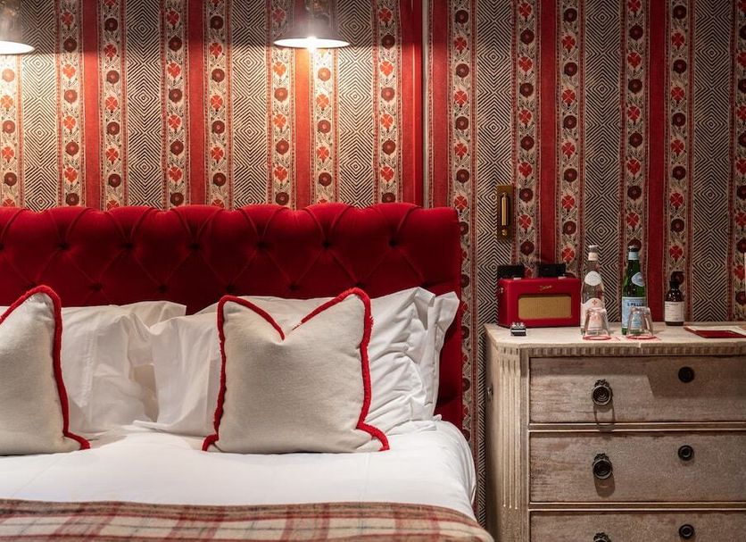 Cotswold Plough Hotel & Restaurant in Bampton bedroom with red tufted headboard and patterned wallpaper