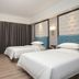 Master Hotel Huizhou twin room with two beds, blue chairs, and floor-to-ceiling curtains