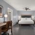 Homewood Suites by Hilton Fresno bedroom with king bed, desk, TV and floor-to-ceiling curtains