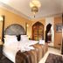 Riad Belle Epoque, Marrakech: ornate guest room with king bed, carved wood furniture and tall drapes