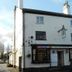 The Green Man in Rugby, white three-story building with black trim and hanging pub sign