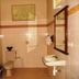 Bali Lovina Beach Cottages bathroom in Buleleng with toilet, sink, shower, and tiled walls