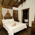 Hacienda el Jibarito in San Sebastián: rustic wood-beamed bedroom with canopy bed and dark floors