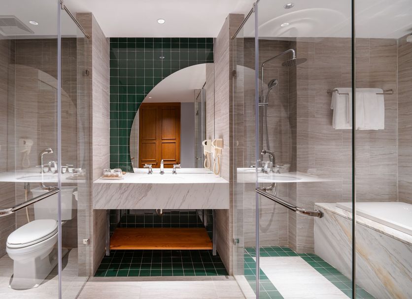 Hadana Boutique Hotel Danang bathroom with glass shower, bathtub, and double vanity in Da Nang