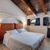 La Terra in Ostuni bedroom with vaulted wood ceiling, bed, arched window, and countryside view