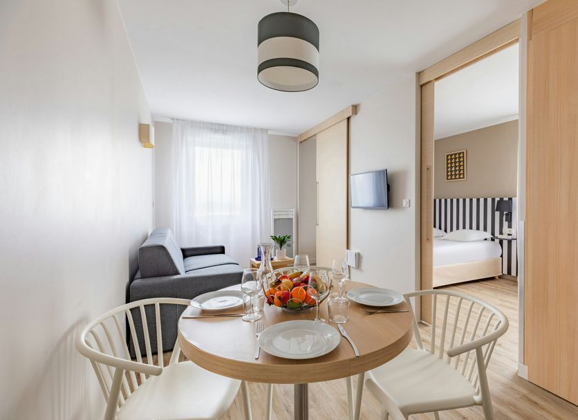 Appart'City Classic Reims Parc des Expositions apartment with dining table, sofa, and bedroom view
