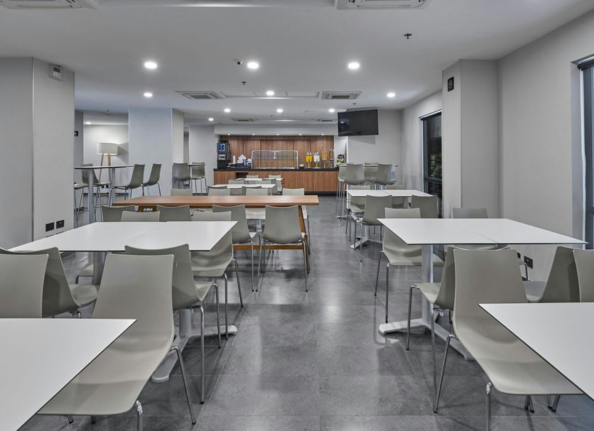 City Express by Marriott Lazaro Cardenas breakfast area with white tables and chairs and a serving counter