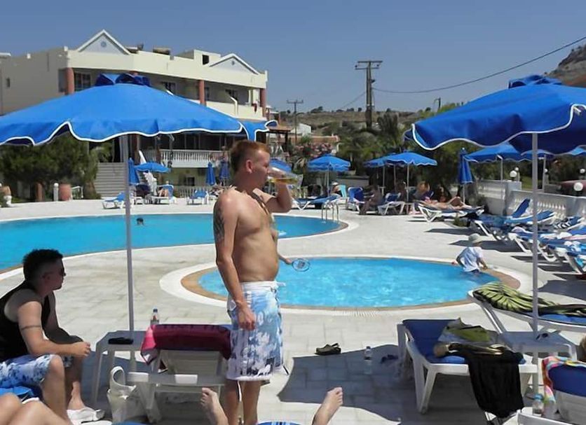 Elvita Beach Hotel in Lardos with outdoor pool, blue umbrellas, and sun loungers
