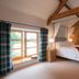 The Old Dairy at Bishops Barton bedroom in Wellington with canopy bed, exposed beams, and large window