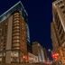 Metcalfe Montreal hotel exterior at night in downtown Montreal, framed by surrounding high-rise buildings