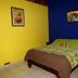 Arte Natura Boutique Hotel in La Fortuna: colorful guest room with bed, blue and yellow walls, and wall art