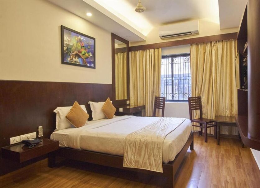 Rkn Hotel Pondicherry guest room with double bed, desk, window curtains and wall-mounted AC