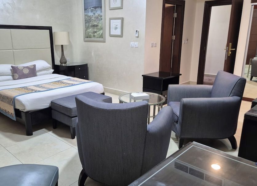 Le Vendome Hotel in Amman guest room with king bed, armchairs, ottoman and seating area