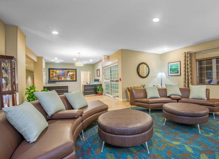Candlewood Suites Jefferson City lobby with brown sectional seating, round ottomans and colorful area rug