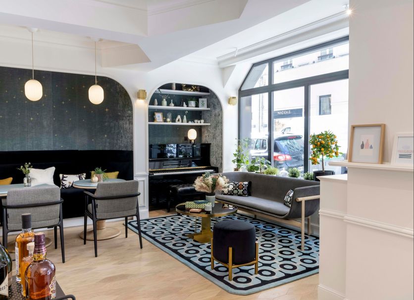 Hotel Louvre Montana Paris lounge with seating, patterned rug, bar shelf and large front window