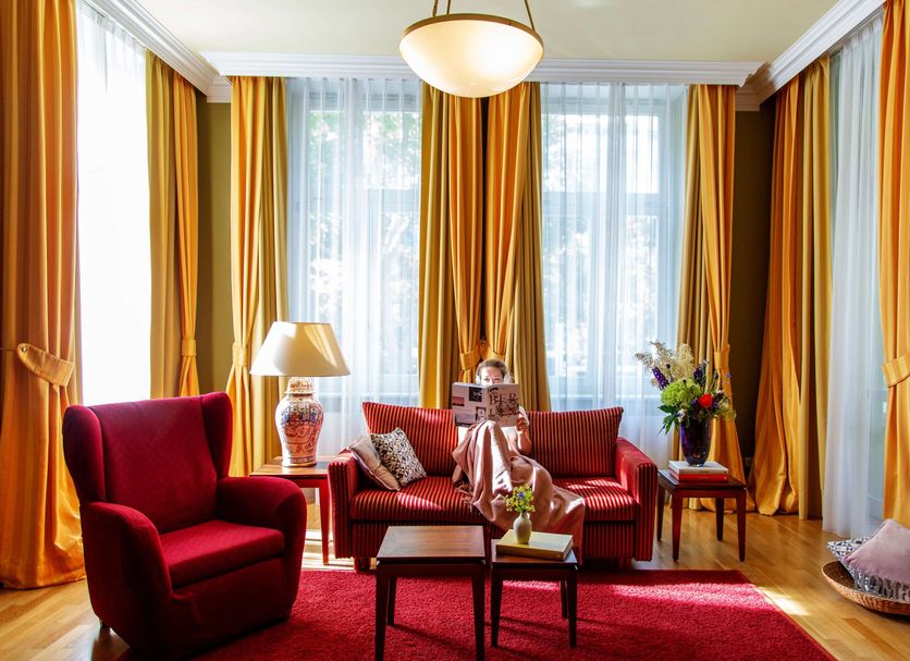 Louisa's Place Berlin living room with red seating, gold curtains, and large windows