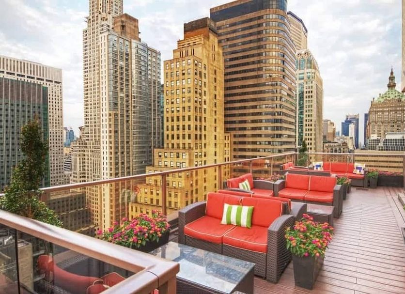 Rooftop terrace at Wyndham Midtown 45 in New York with red lounge seating and city skyline views