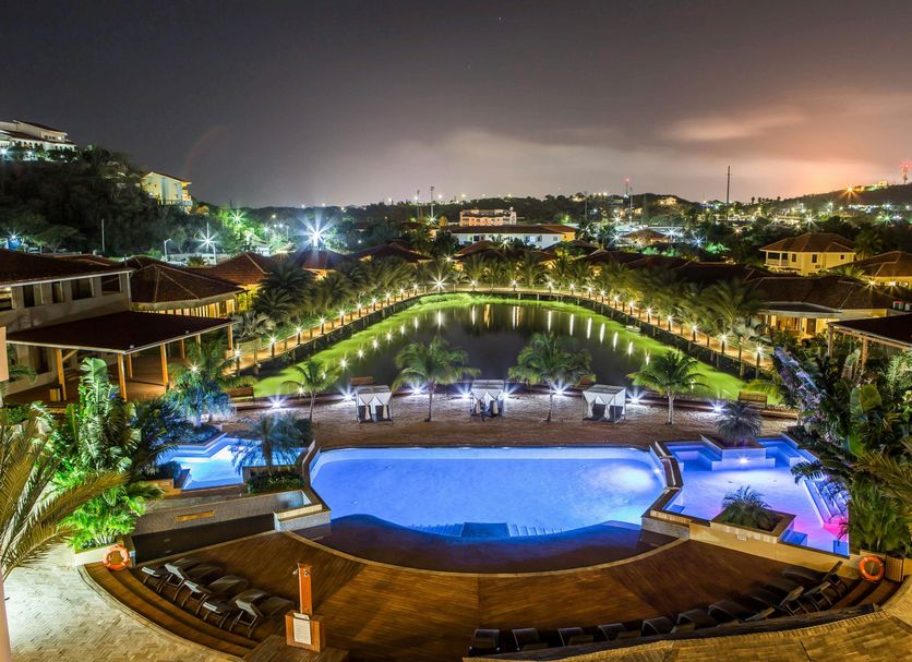 Acoya Curacao Resort, Villas & Spa in Willemstad with lit pool, landscaped gardens and evening skyline view