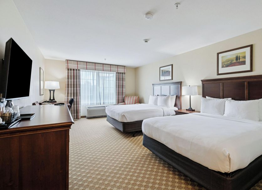 Country Inn & Suites by Radisson, Covington, LA guest room with two beds and a window view