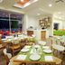 Hb CÓrdoba dining area with wooden tables, green chairs, and large windows in Córdoba