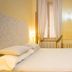 Domus Pinciana Rome guest room with double bed, wardrobe, mirror, and window with curtains