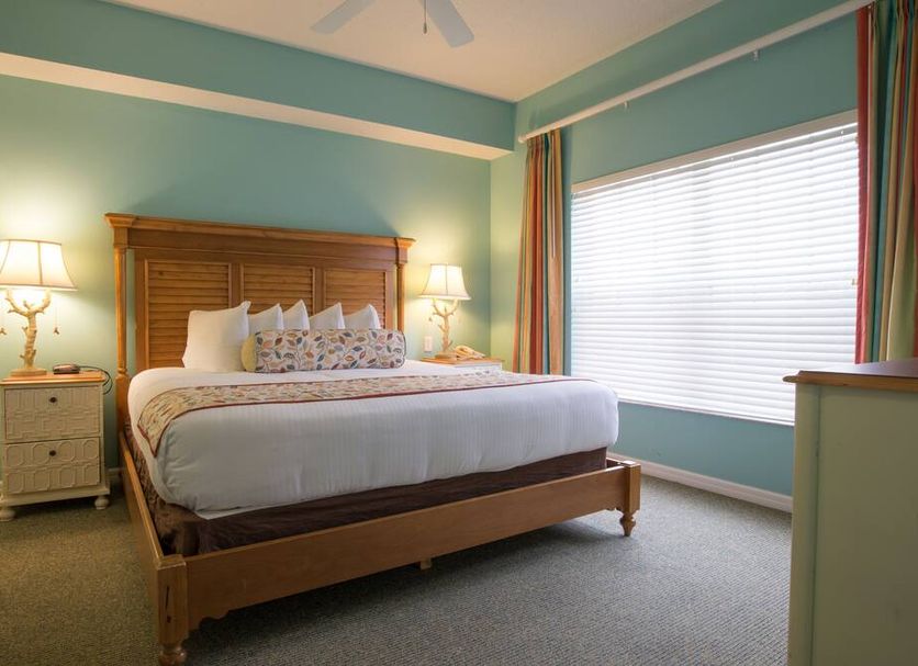Barefoot Suites Kissimmee bedroom with king bed, bedside lamps, and large window with blinds