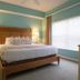 Barefoot Suites Kissimmee bedroom with king bed, bedside lamps, and large window with blinds
