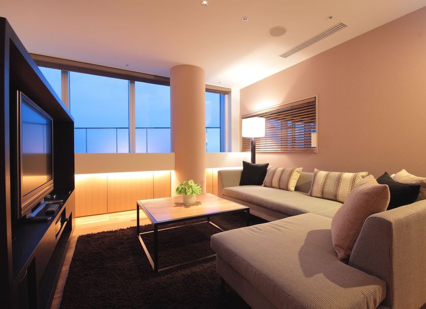 Hotel Arc Riche Toyohashi suite with large windows, sectional sofa, and city view in Toyohashi.