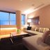 Hotel Arc Riche Toyohashi suite with large windows, sectional sofa, and city view in Toyohashi.