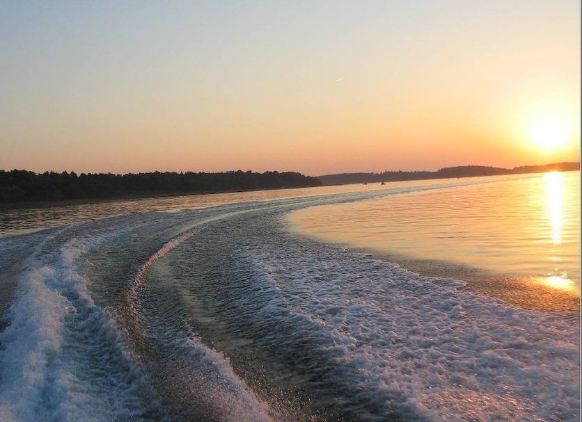 Waren Müritz Hotel Harmonie in Waren: sunset view over a calm lake with boat wake and shoreline