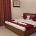 Hotel Maiden Residency in Ghāziābād: neatly made double bed with red accents and bedside table