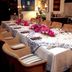 Pinctada Mcalpine House Broome dining room with set table, wicker chairs, and pink floral centerpiece