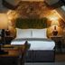 The Falkland Arms in Chipping Norton room with a green tufted headboard, bedside lamps, and floral wallpaper