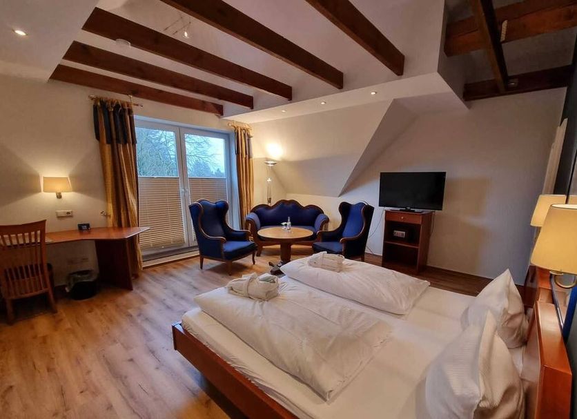 Hotel Osterkrug in Husum guest room with twin beds, seating area, TV, and exposed wood beams