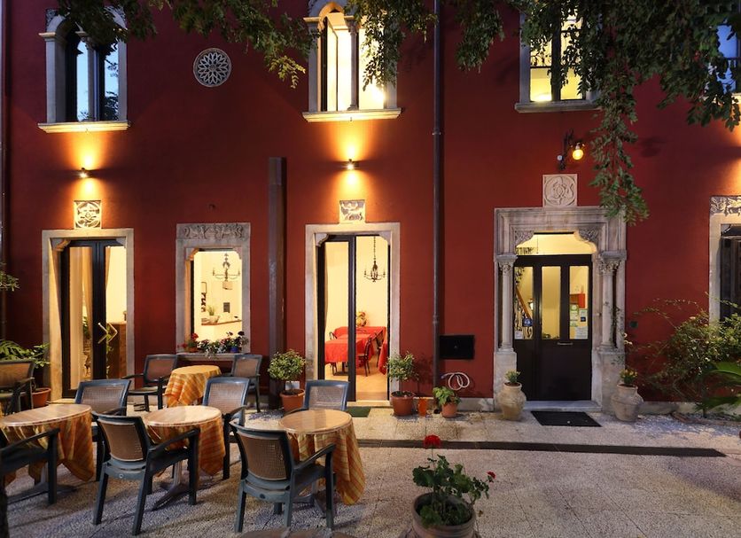 Villa Astoria in Taormina, illuminated red courtyard with outdoor dining tables and chairs at night