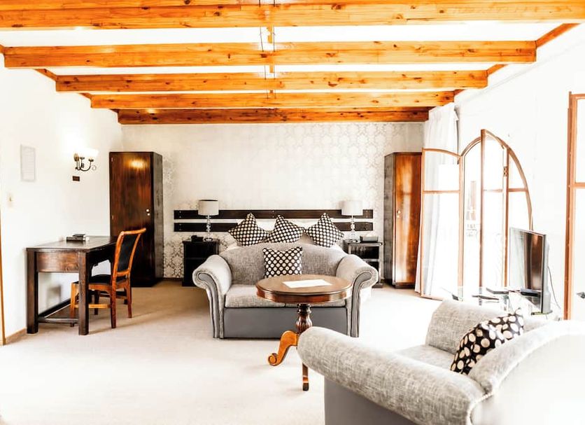 Casa Blanca Hotel in Windhoek: bright lounge with exposed wooden beams, sofas, desk and arched windows