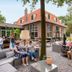 Stayokay Soest outdoor patio with guests, lounge seating, and a brick building in Soest
