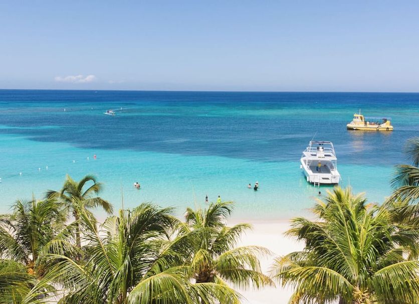 Henry Morgan Hotel & Beach Resort in Coxen Hole with palm trees, white sand beach, and turquoise ocean view