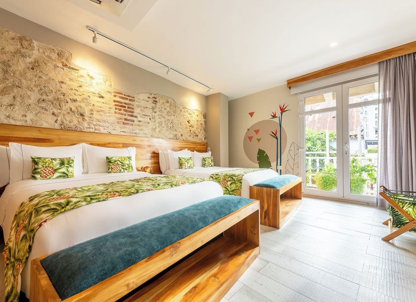 Townhouse Boutique Hotel in Cartagena room with two beds, stone accent wall, and balcony doors