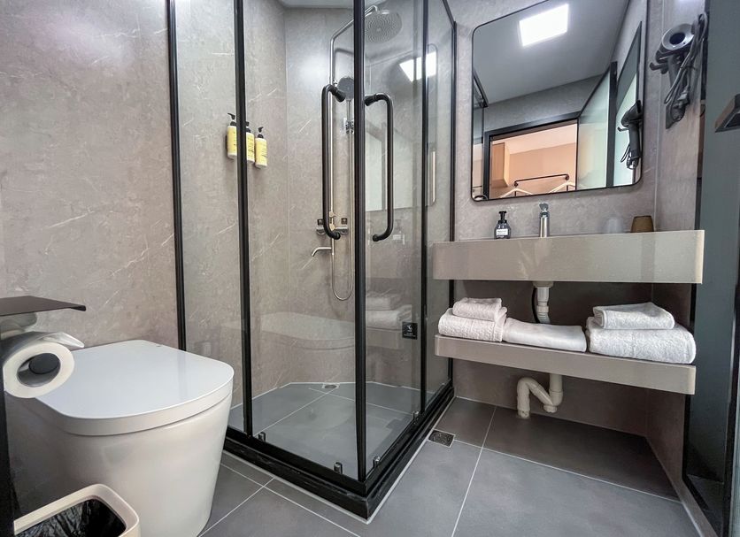 Shanghai Joyful Star Hotel bathroom with glass shower, wall-mounted sink, and toilet in Shanghai